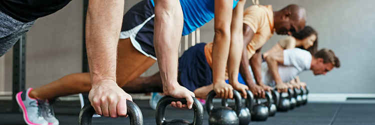 Group Fitness Classes - Group of men and women exercising with kettlebells.